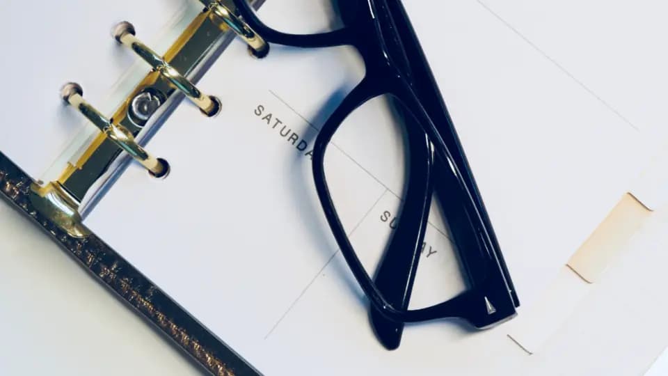 An open ring-bound planner with glasses lying across the pages, used to plan a start date