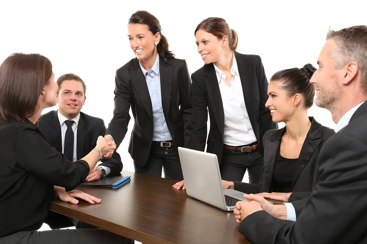 Two people shaking hands in an office, as employers return to in-person interviews