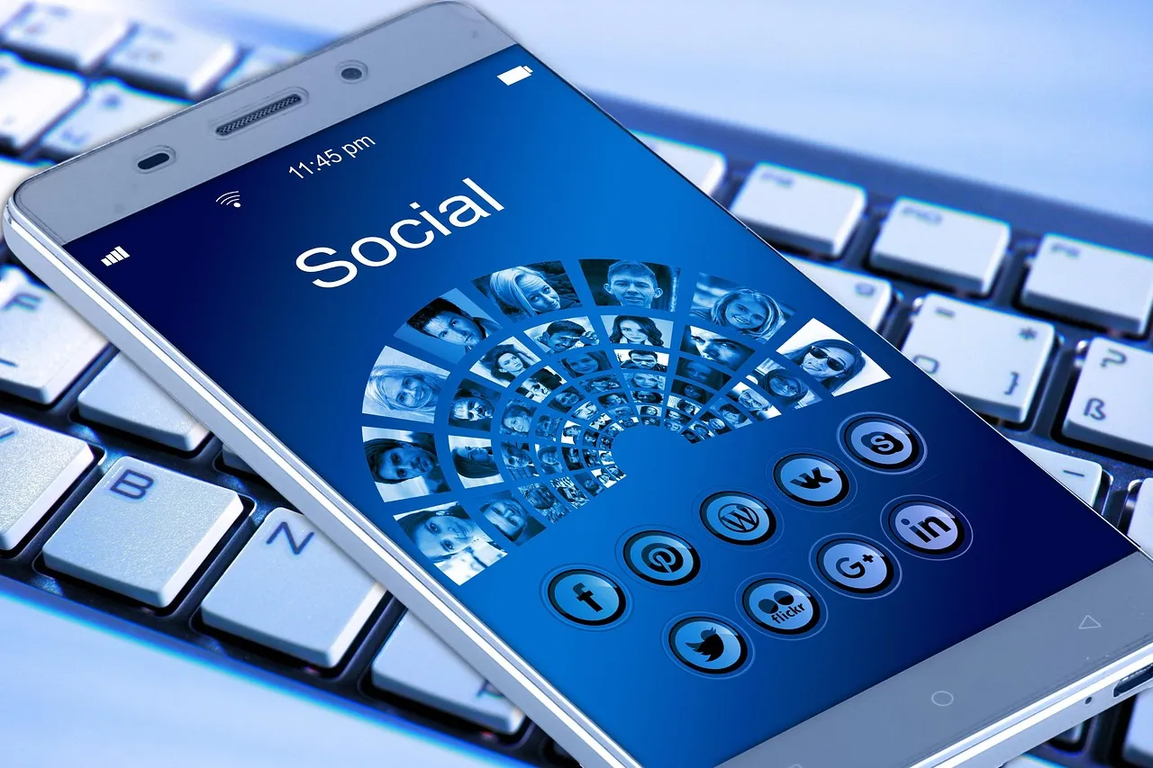 Smartphone on a keyboard showing a Social screen with profile photos and social network icons