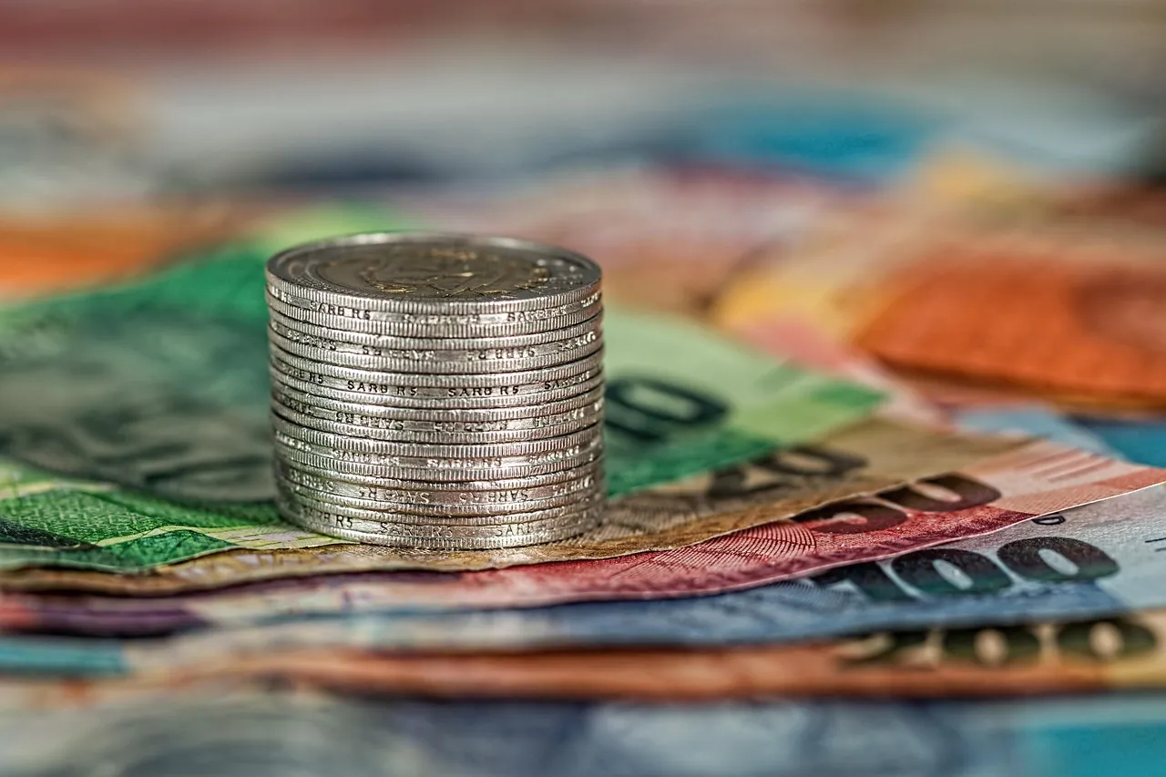 Stack of silver coins on banknotes from several currencies
