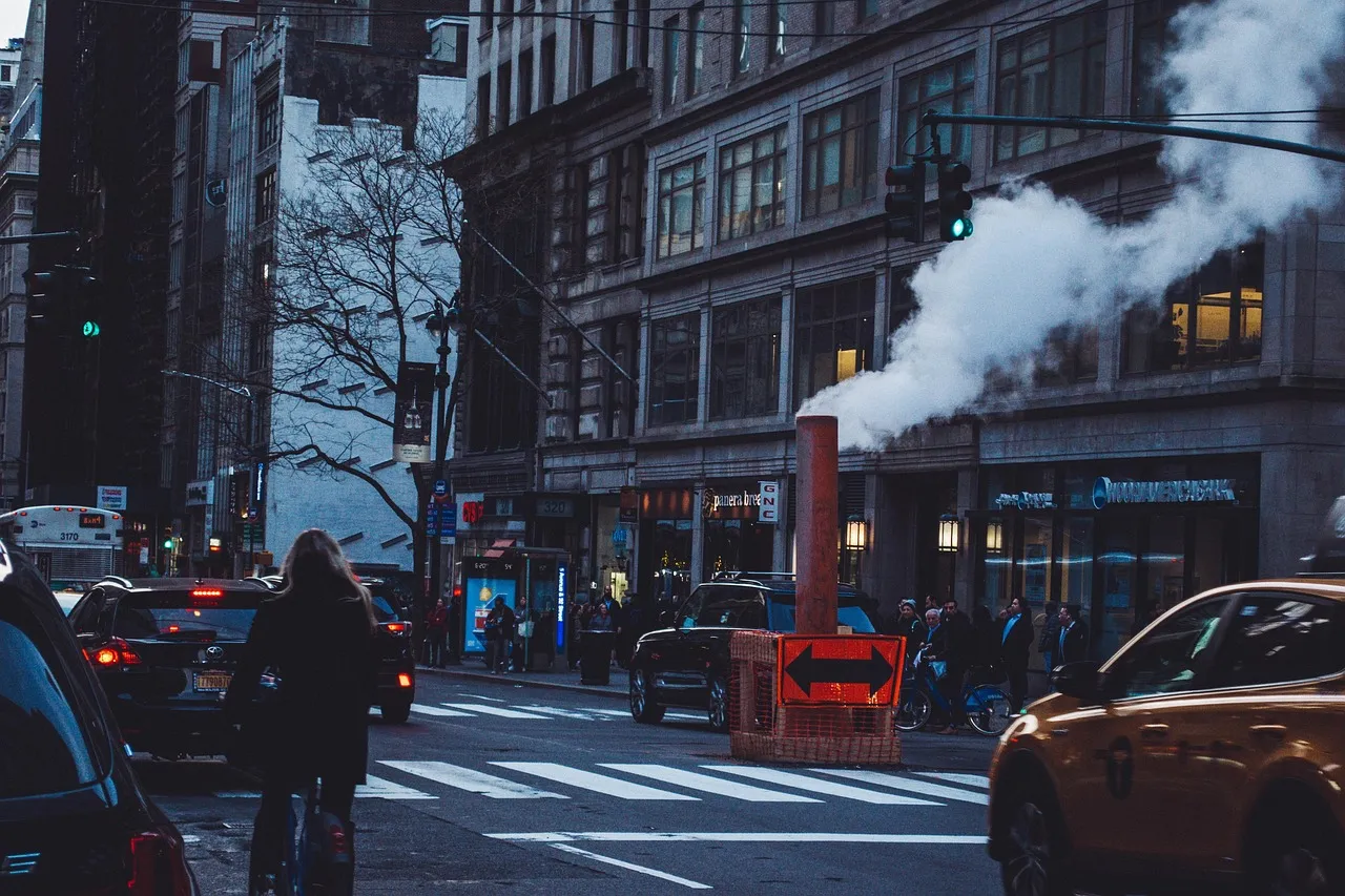 New York City street crossing with traffic and steam rising from a vent