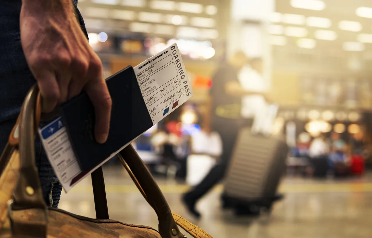 Traveller holding a passport and boarding pass while carrying a leather bag in an airport