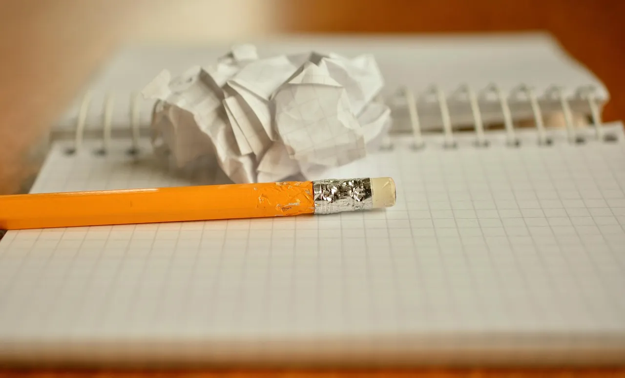 Crumpled sheet of paper and a pencil on a grid notebook