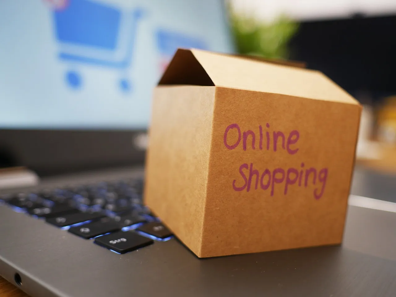 Small cardboard box marked Online Shopping sitting on a laptop keyboard