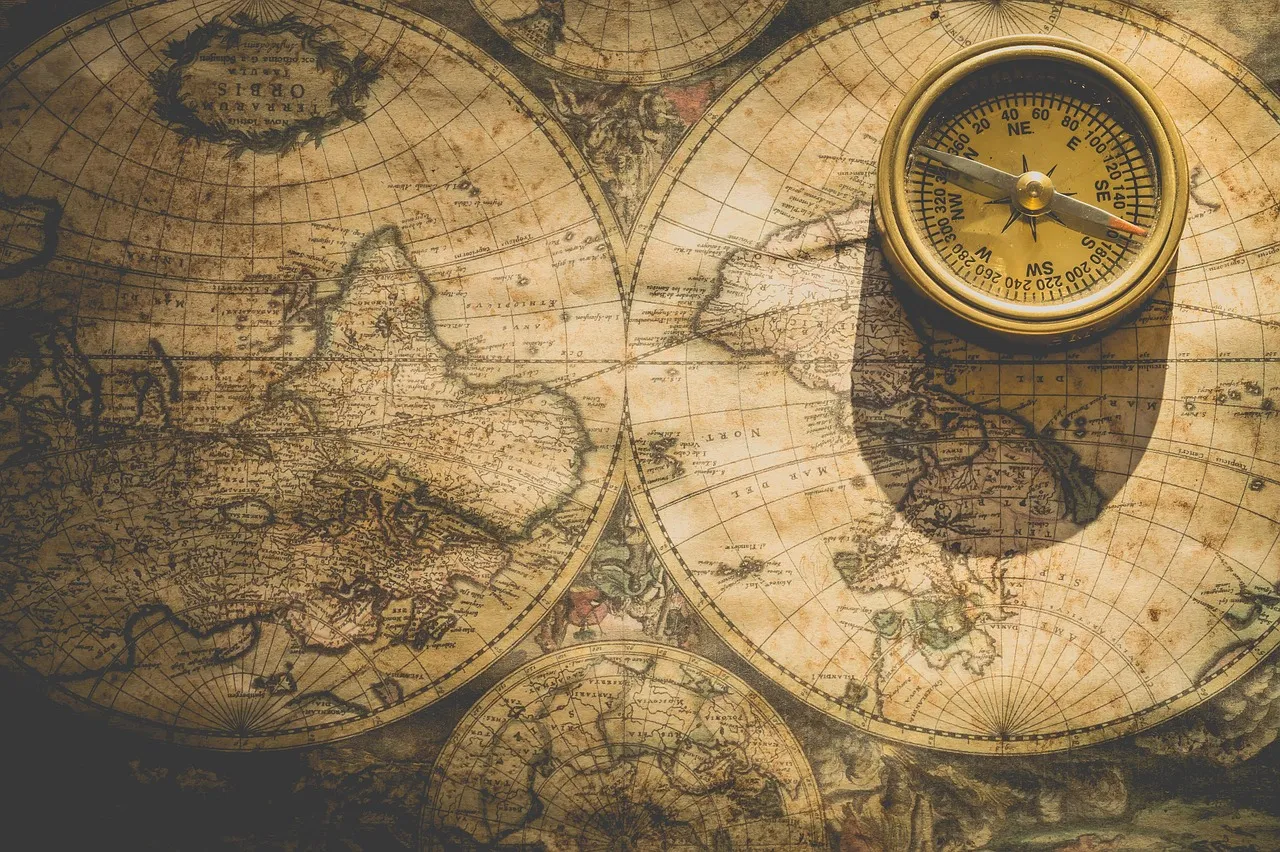 Antique world map in two hemispheres with a brass compass resting on top