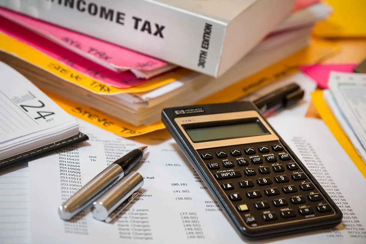 Calculator, pens and an income tax book on a pile of paperwork