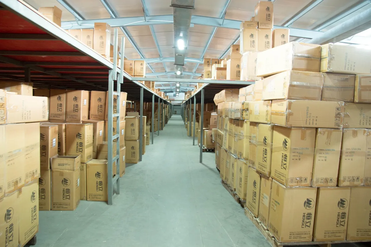 Tall warehouse shelving stacked with cardboard boxes along a wide aisle in a distribution centre