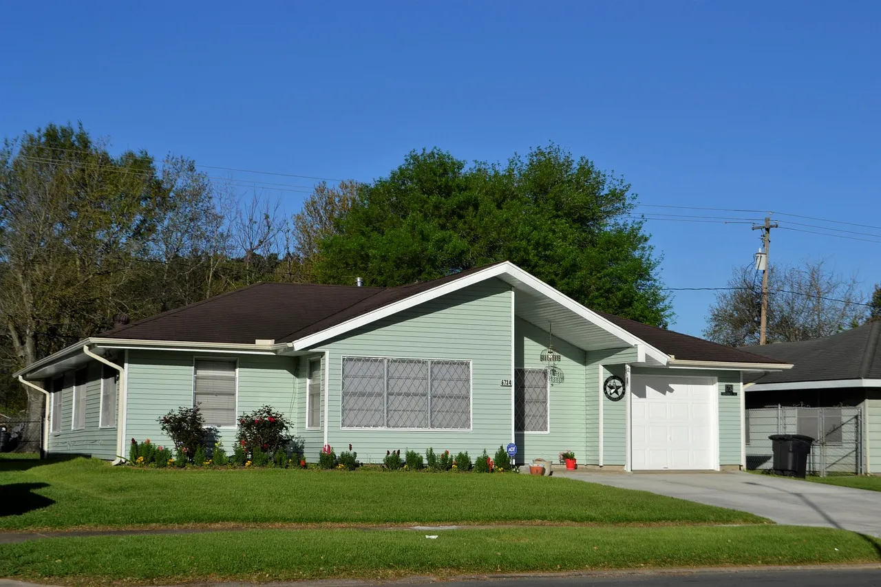 Single-story green suburban house with a lawn and driveway