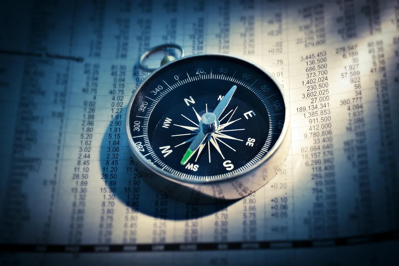 A compass resting on the financial pages of a newspaper, a reminder to read the jobs report for direction rather than one headline