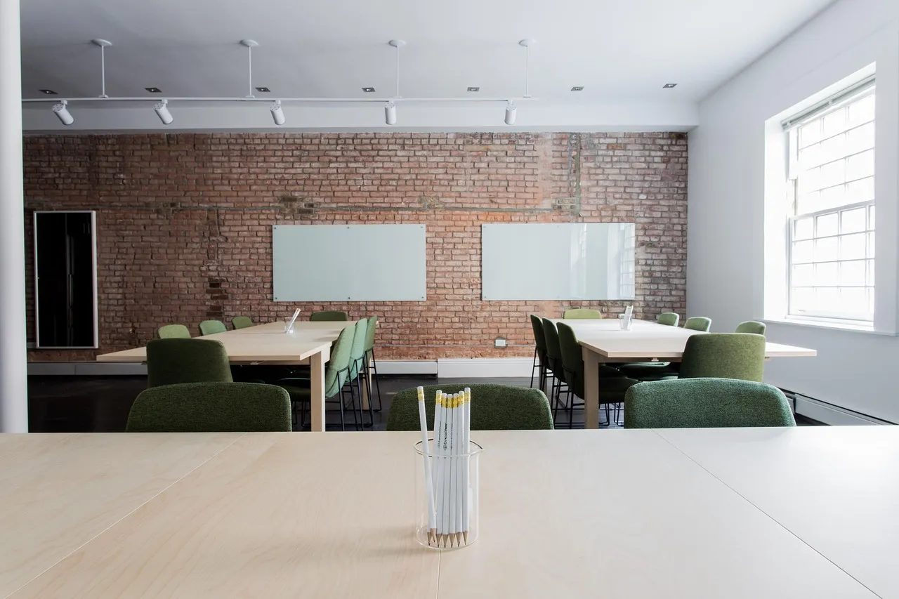 Empty open-plan office with long desks and green chairs